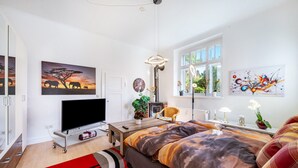 Een slaapkamer met een bed, een televisie, een raam en kunstwerken aan de wanden.
