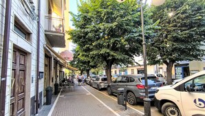 Une rue bordée de voitures garées et, sur le côté gauche, un café appelé « La Pineta ».