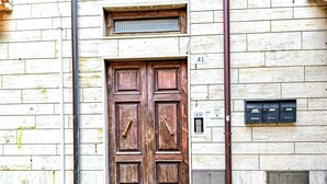 Une porte à deux battants en bois, dotée d’une poignée en laiton, une boîte aux lettres et une plaque numérotée « 41 » sur la façade d’un immeuble.