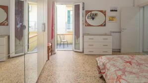 Une chambre à coucher comprenant un lit, une commode, un miroir et une porte donnant sur un balcon.