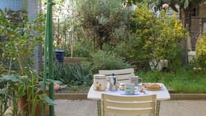 Une table avec une chaise, une cafetière, une tasse et une assiette contenant de la nourriture.