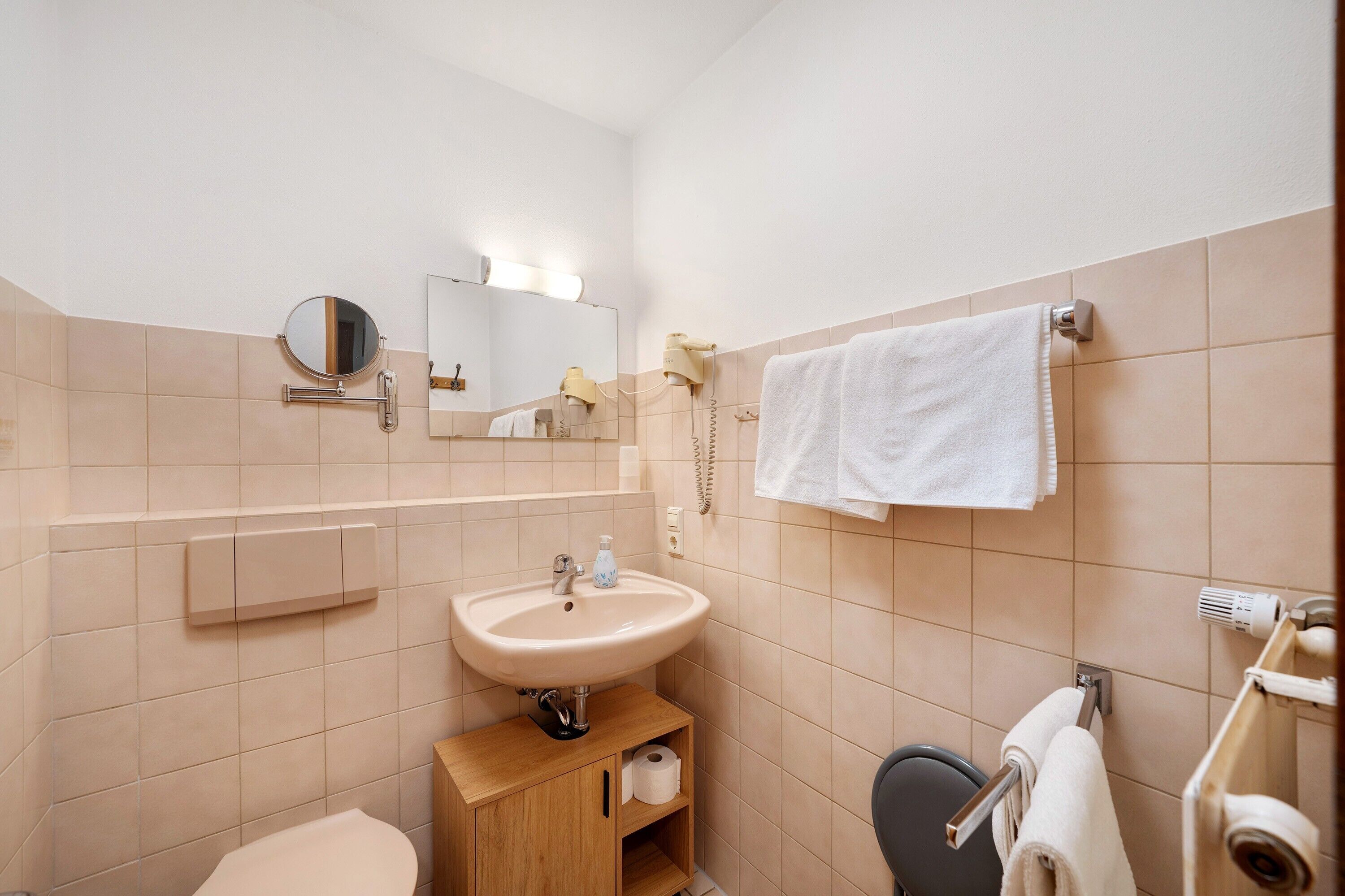 Une salle de bain équipée d’un lavabo, d’un miroir, d’un porte-serviettes et de toilettes.