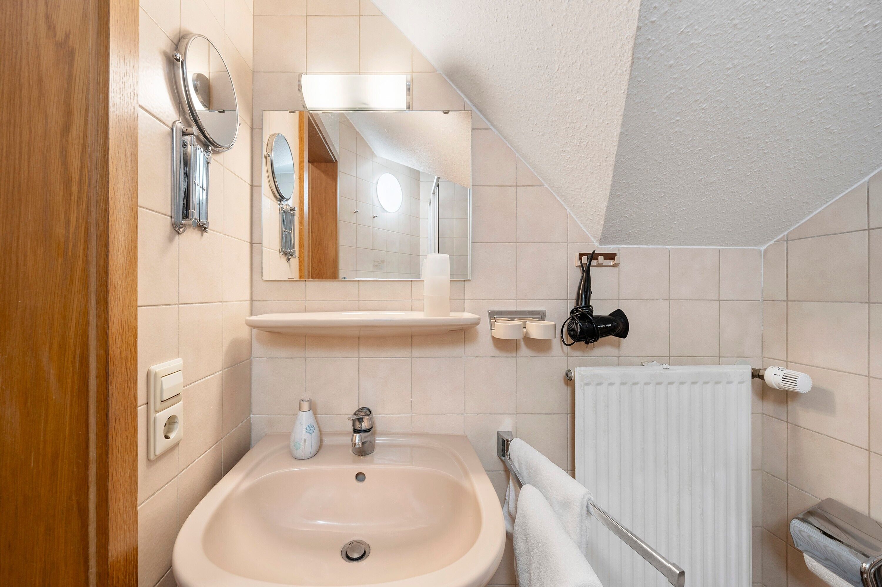 Ein Badezimmer mit Waschbecken, Spiegel, Handtuchhalter und einem Handtuch an der Wand.