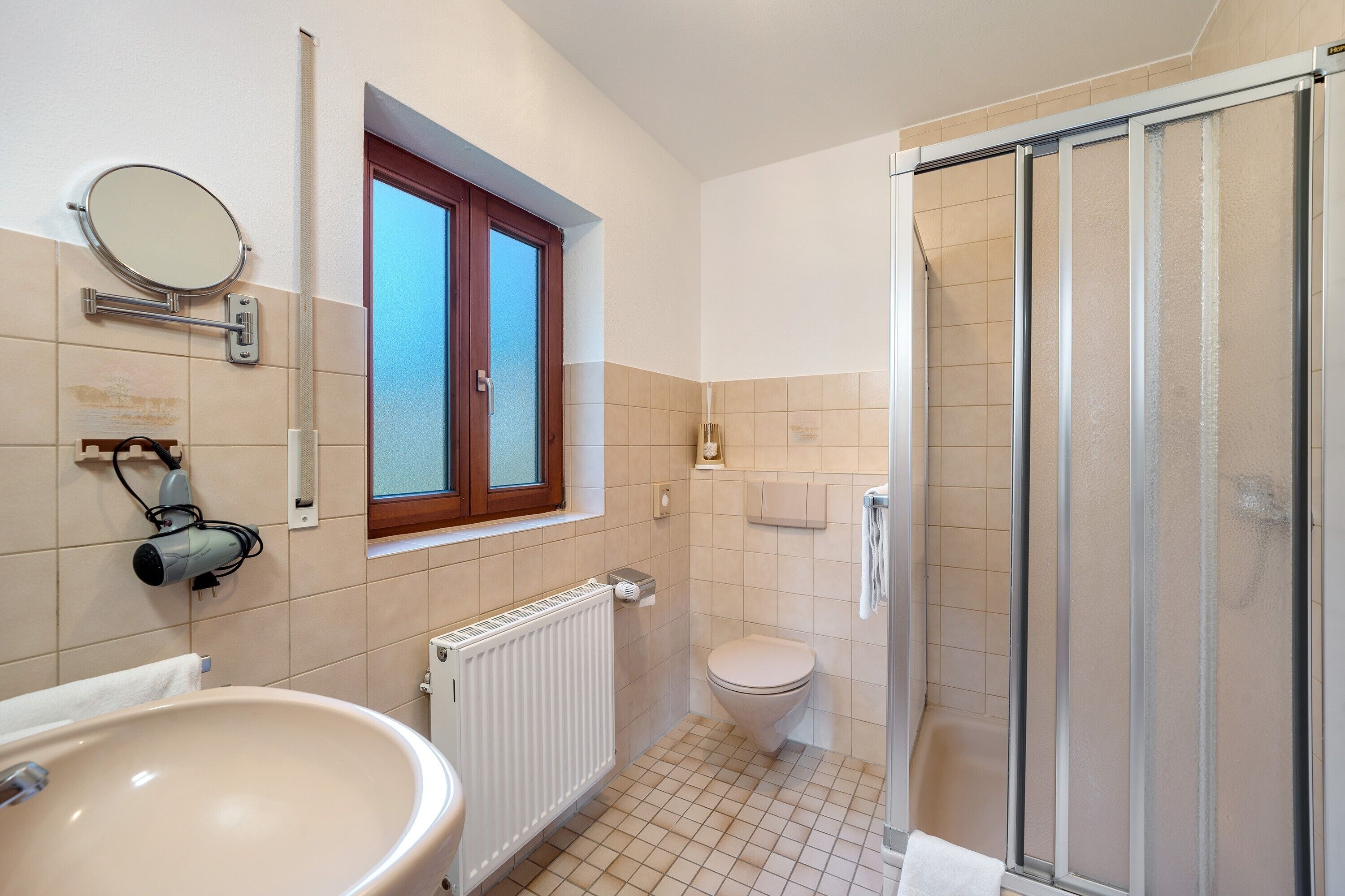 Ein Badezimmer mit Waschbecken, Toilette, Dusche und einem Fenster.