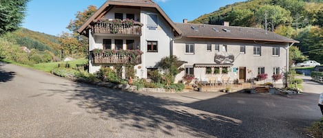 A two-story building with a balcony, a small garden, and a clear sky.