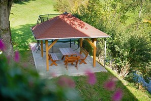 A gazebo with a tiled roof, wooden benches, and a picnic table. - Apartment 'No. 2.1 Rotkelchen' with Shared Terrace, Shared Garden and Wi-Fi (Freiamt)