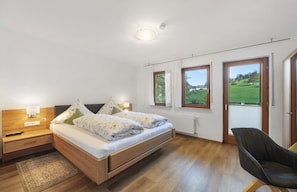 A bedroom with a bed, bedside lamps, a chair, and large windows with a view of a green landscape. - Apartment 'No. 2.1 Rotkelchen' with Shared Terrace, Shared Garden and Wi-Fi (Freiamt)