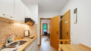 A narrow kitchen with a sink, a stove, and a wooden table. - Apartment 'No. 2.1 Rotkelchen' with Shared Terrace, Shared Garden and Wi-Fi (Freiamt)