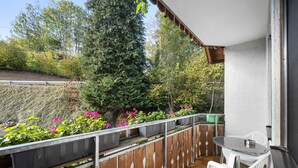 A balcony with a table and chairs, surrounded by potted plants and flowers. - Apartment 'No. 2.1 Rotkelchen' with Shared Terrace, Shared Garden and Wi-Fi (Freiamt)