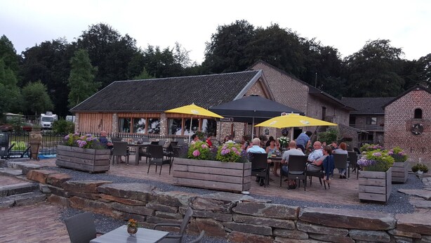 Un espace extérieur aménagé avec des tables et des chaises, entouré de jardinières fleuries.