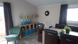 Un espace repas comprenant une table, des chaises, une bibliothèque et un élément décoratif fixé au mur.
