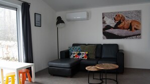Un salon moderne avec un canapé en cuir noir, une table blanche et des tabourets colorés.