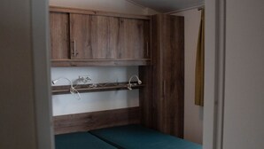 Ein kleines Zimmer mit einem Bett, Holzschränken und einer Deckenleuchte.