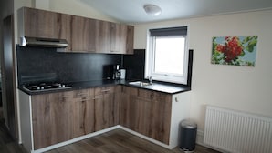Une cuisine moderne avec des meubles en bois, une cuisinière à gaz, un évier et une fenêtre.