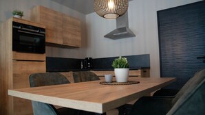 Eine moderne Küche mit Holzausstattung, Backofen, Kaffeemaschine und Essbereich mit Holztisch und Stühlen.