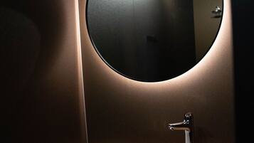 A modern bathroom with a round mirror, a white sink, and a wooden countertop.