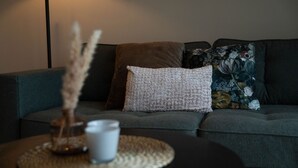 A living room with a grey sofa, a white knitted pillow, and a floral cushion.