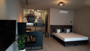 A modern bedroom with a bed, bedside tables, a desk, and a potted plant.