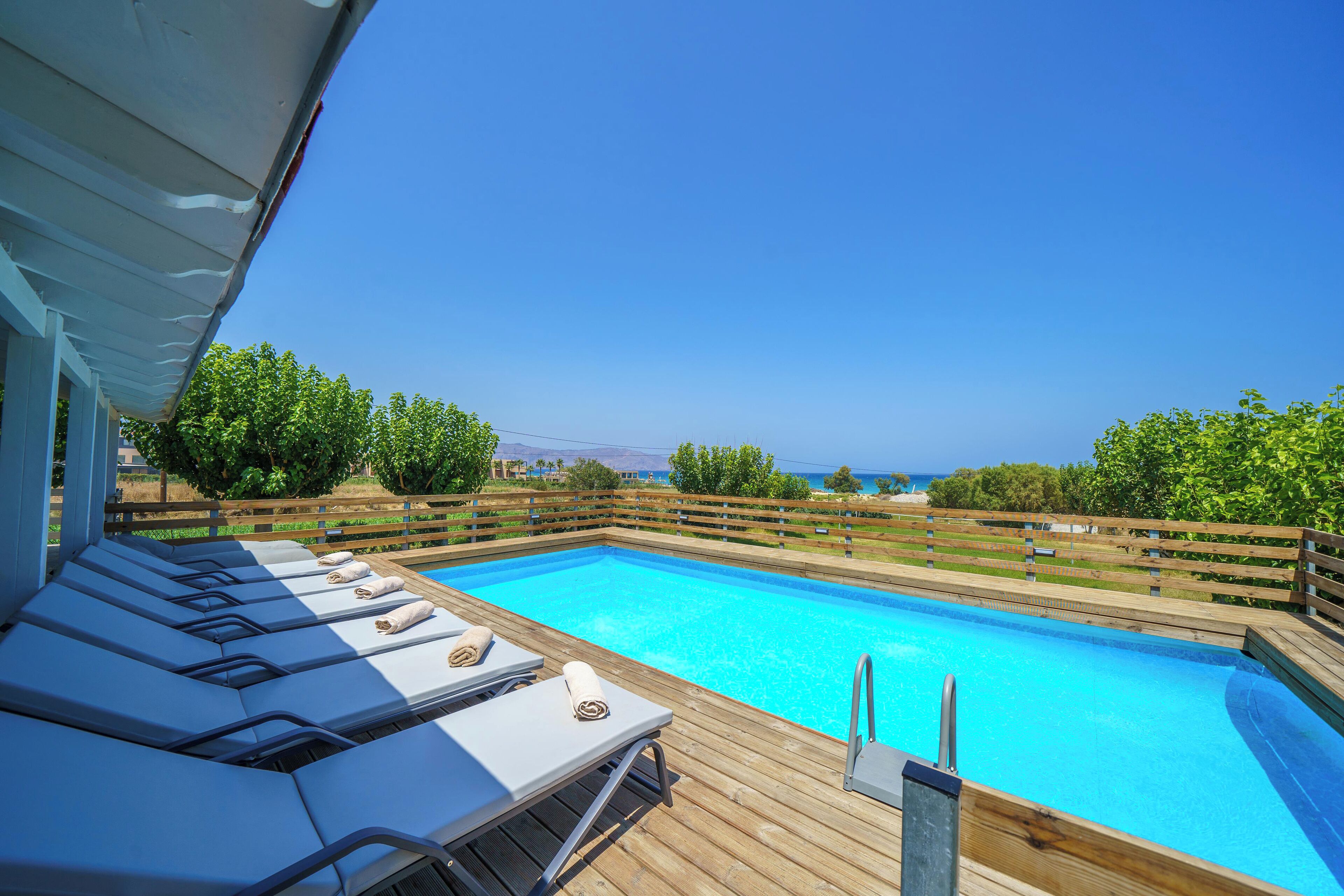 Eine Holzterrasse mit Liegestühlen und einem Swimmingpool.