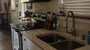 A kitchen with white cabinets, a stainless steel sink, and a microwave.