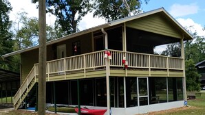 A two-story house with a balcony, a covered porch, and a small boat docked outside.