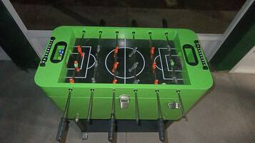 A green foosball table with a soccer field design, mounted on a wall.
