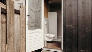 A wooden exterior with a white door leading to a bathroom featuring a toilet and a shower. - Solglimt 2 pers holiday home with stunning views (Callantsoog)