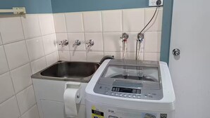 Uma lavanderia compacta com máquina de lavar, pia e suporte para papel higiênico.