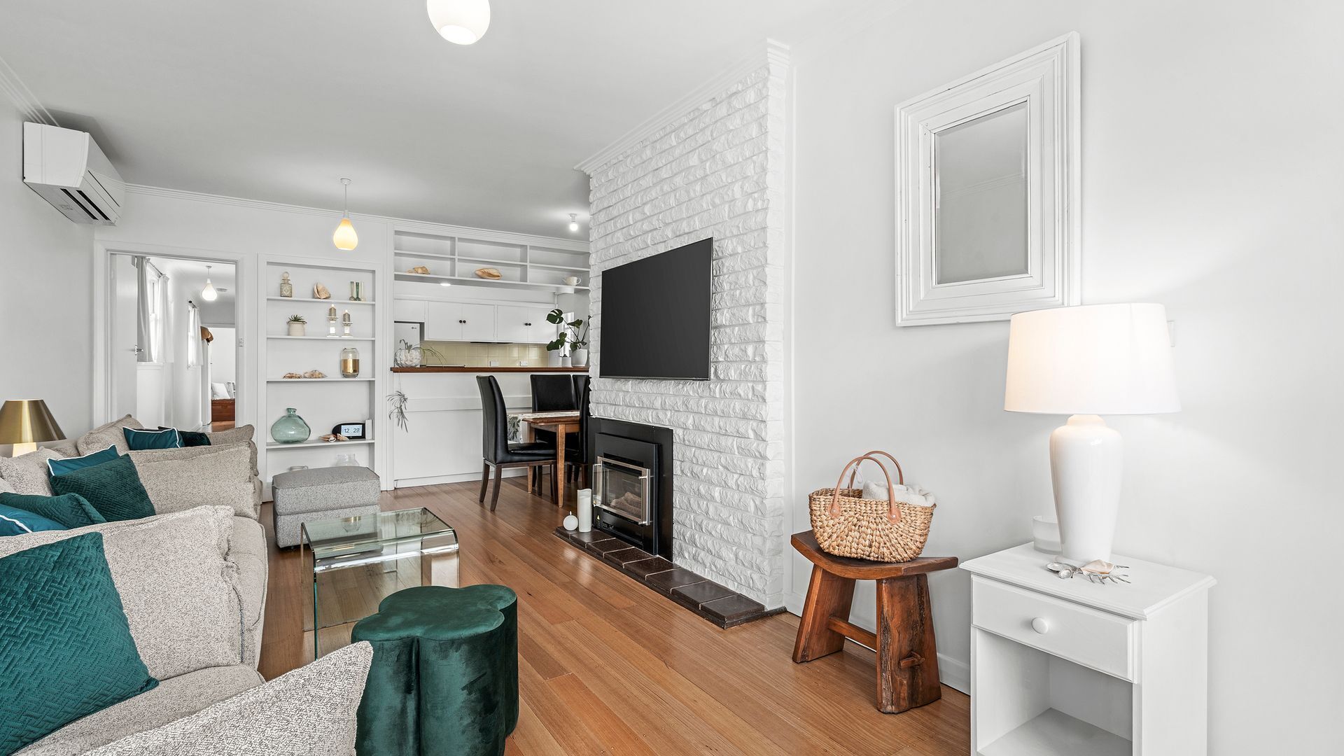 A modern living room with a fireplace, a dining area, and a kitchen with white cabinetry.