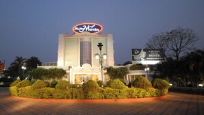 A hotel with a prominent neon sign, a well-maintained garden, and a paved entrance area. - The New Marrion (Bhubaneshwar)