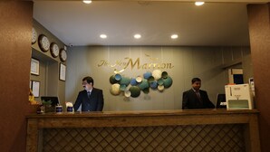 A reception desk with two staff members, a wall clock, and a decorative wall piece. - The New Marrion (Bhubaneshwar)