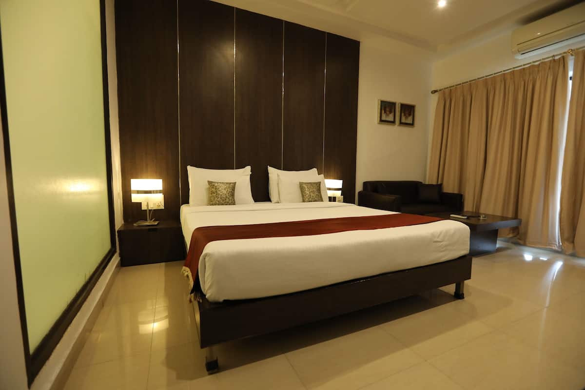 A large bed with white linens, a dark headboard, and two bedside tables with lamps.