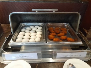 A buffet with labeled containers for boiled eggs and chicken cutlet.