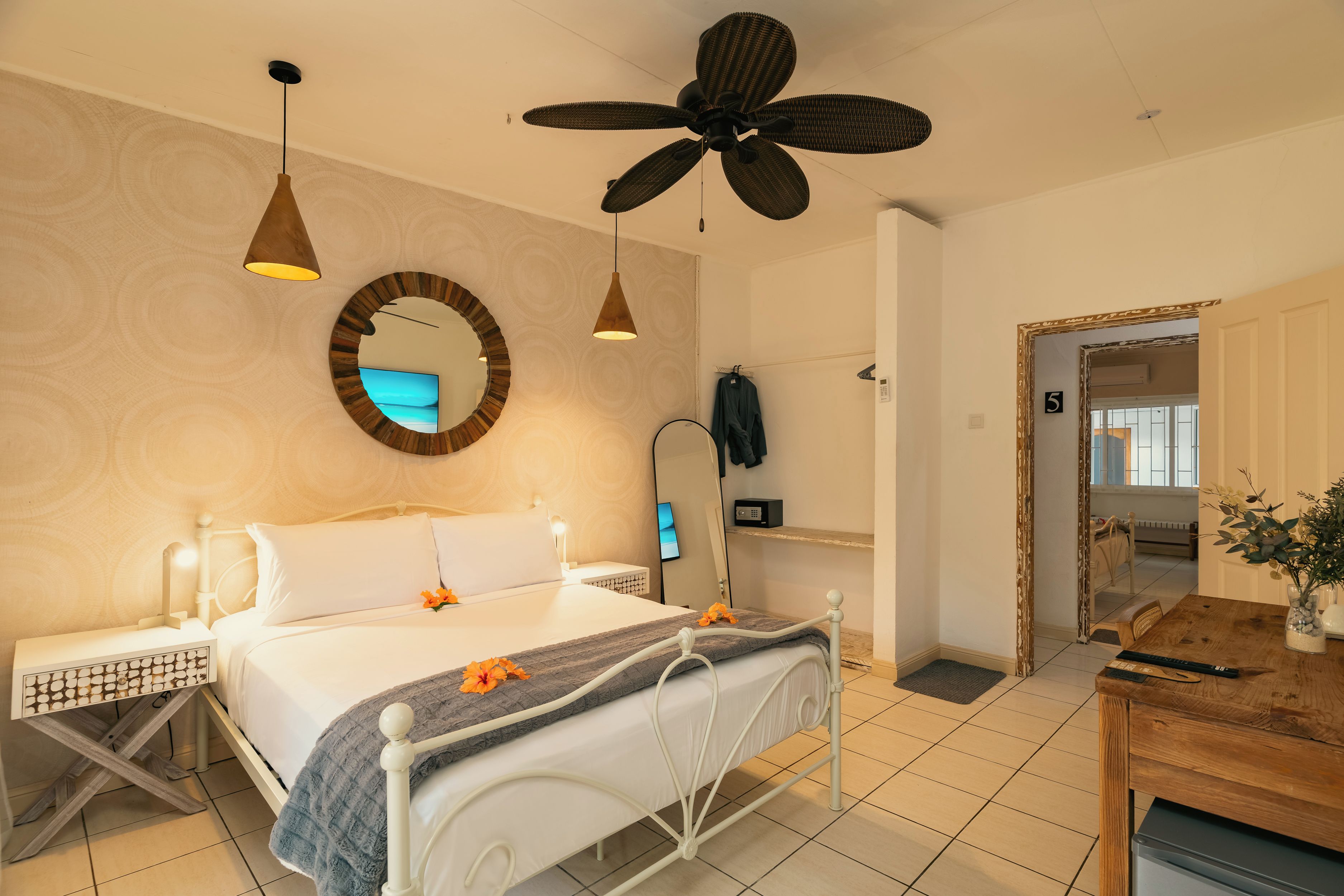 A hotel room with a bed, bedside table, lamp, ceiling fan, and a mirror.