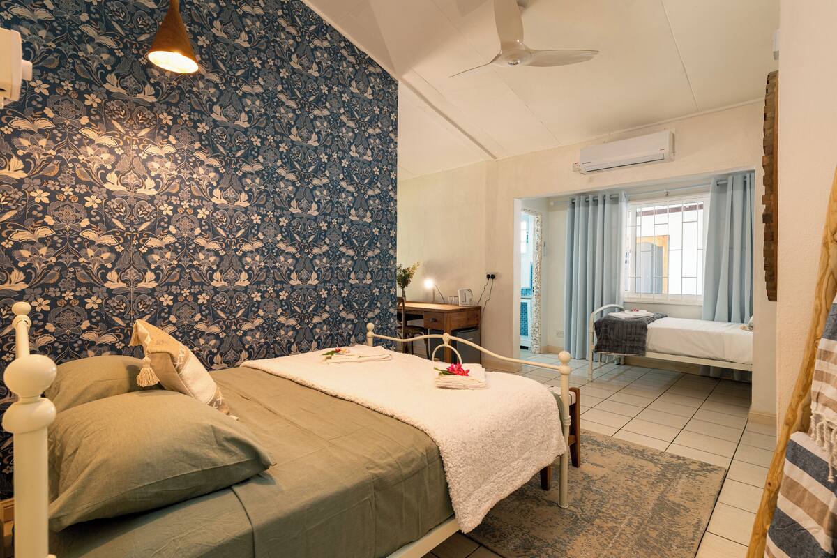Een slaapkamer met een bed, een bureau en een raam met gordijnen.