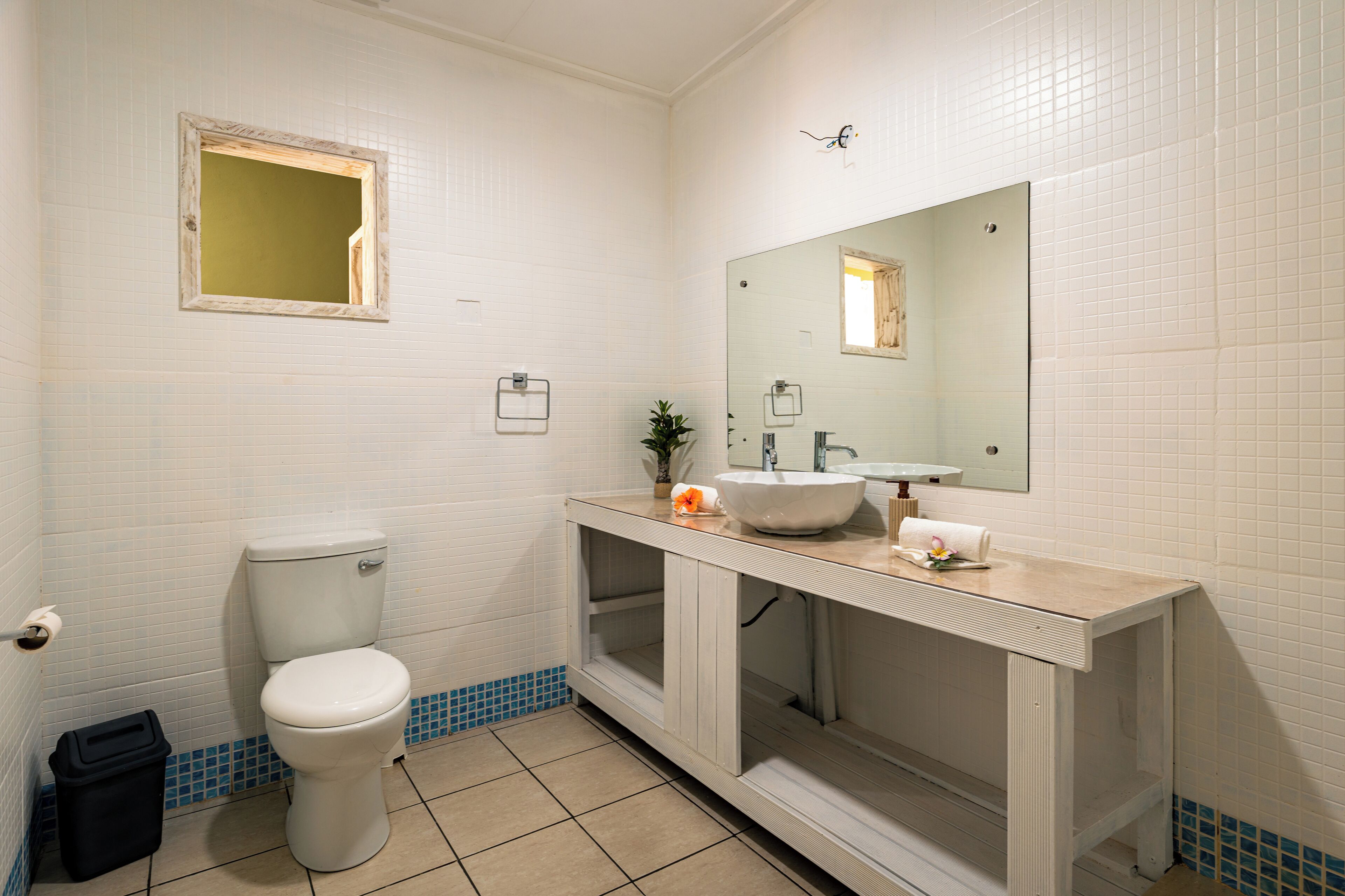 A bathroom with a toilet, sink, mirror, and blue-tiled floor.