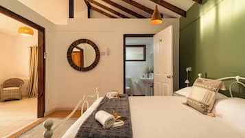 A bedroom with a bed, a round mirror, a hanging light fixture, and a view of the bathroom.