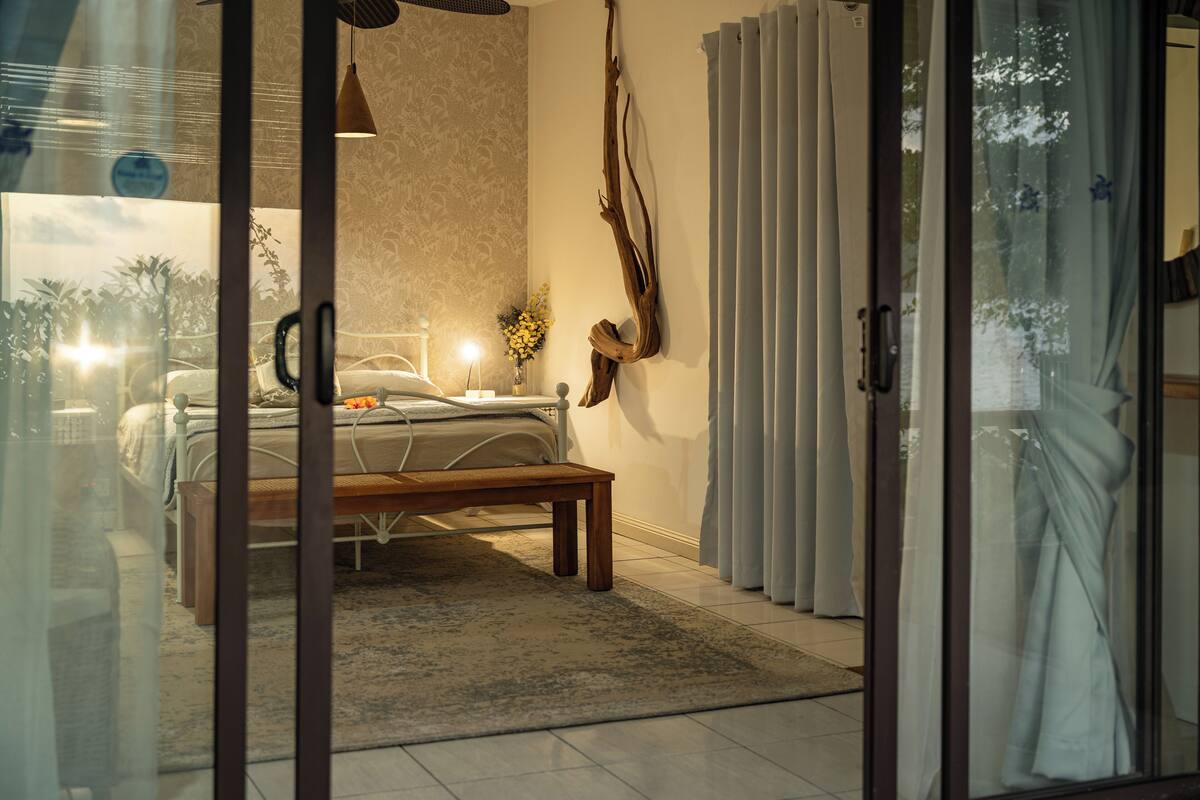 Een slaapkamer met een bed, nachtkastje en een raam met gordijnen.