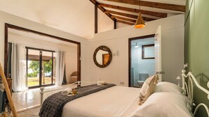 A bedroom with a bed, a wooden headboard, a large mirror, and a view of the outdoors. - Beach House Beau Vallon (Mahe Island)