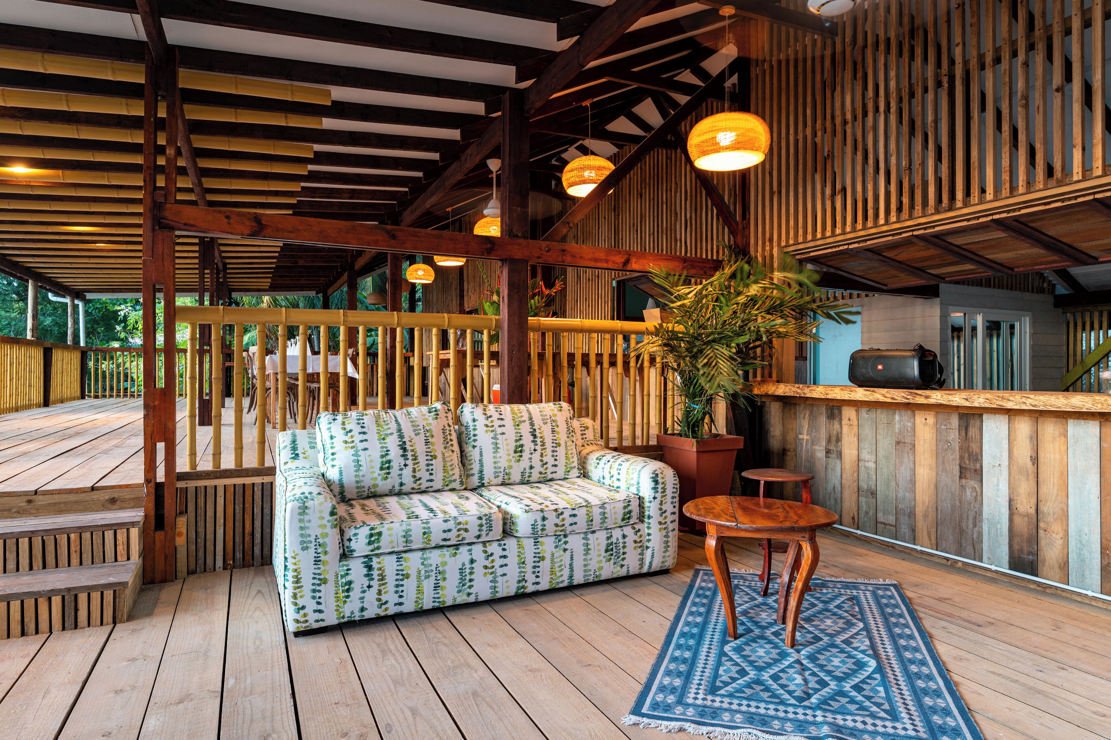 A wooden deck with a sofa, a table, and a potted plant.