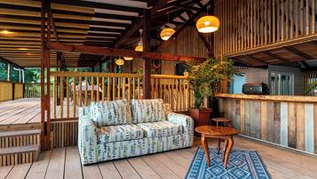 A wooden deck with a sofa, a table, and a potted plant.