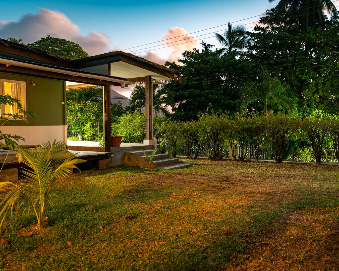 Una casa con porche cubierto, un jardín pequeño y vista al cielo.