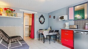 Ein kompakter Wohnbereich mit einer Küchenzeile, einer Essecke mit Tisch und Stühlen, einer Couch und einem roten Schrank.