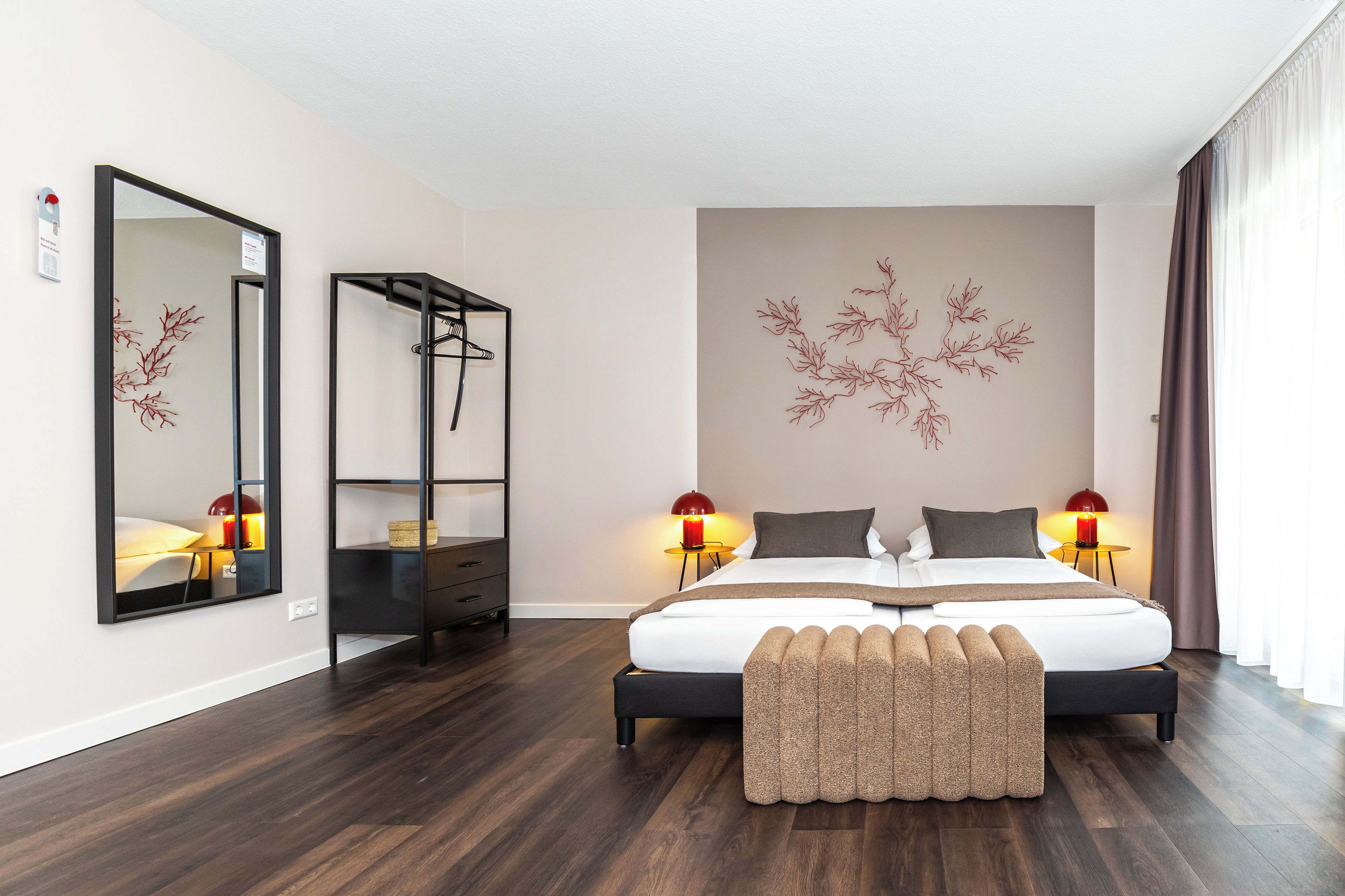 Een moderne slaapkamer met een groot bed, bedlampen, een kledingkast en een decoratief wandobject.