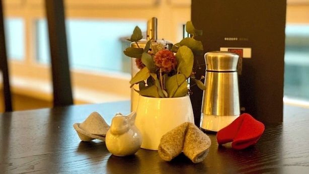 A wooden table with a white vase containing flowers, a silver coffee pot, and small decorative items. - Hotel Friedrichstraße  (Lampertheim)