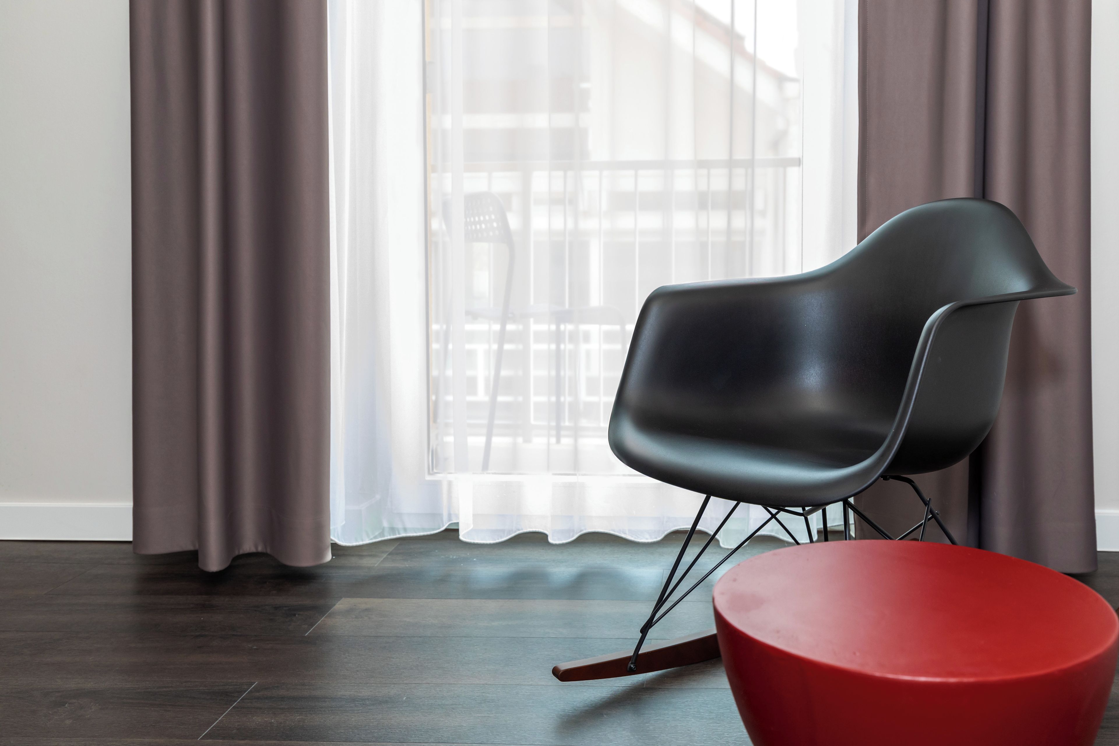 A modern room with a black chair and a red stool.