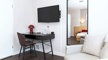 Habitación de hotel con escritorio, silla y un espejo grande.