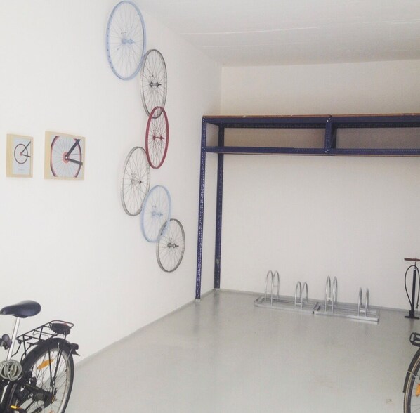 Ein Zimmer mit weißer Wand, einem Fenster mit blauer Rahmung und einem Fahrradständer.