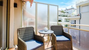A balcony with wicker chairs, a small round table, and a view of neighboring buildings. - Apartment with Private Terrace, Wi-Fi and Air Conditioning (Nice)