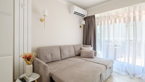 A modern room with a sofa, a small table with a remote, and a wall-mounted air conditioner. - Apartment with Private Terrace, Wi-Fi and Air Conditioning (Nice)
